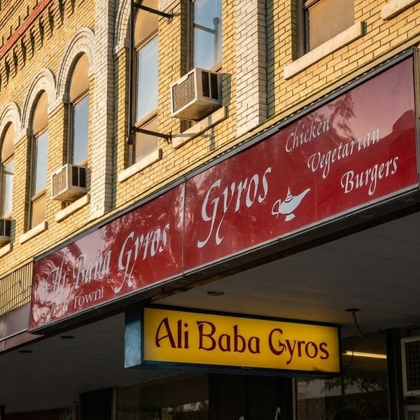 Exterior of Ali Baba Gyros restaurant with red and yellow signs on a brick building.